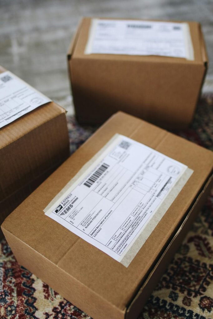 Brown cardboard boxes with labels stacked on a patterned carpet, emphasizing delivery and logistics.